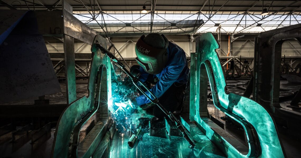 Fotografia corporate industriale: operaio salda una struttura metallica in officina